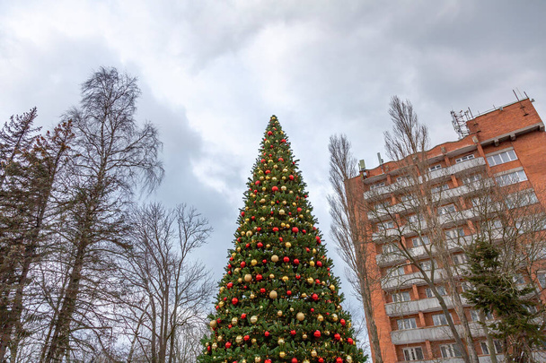 Slavnostní hračky visí na větvi syntetického vánočního stromku s jasným elektrickým věncem - Fotografie, Obrázek