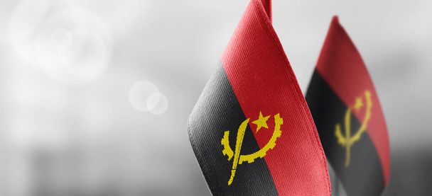 Małe flagi narodowe Angoli na jasnym, rozmytym tle - Zdjęcie, obraz