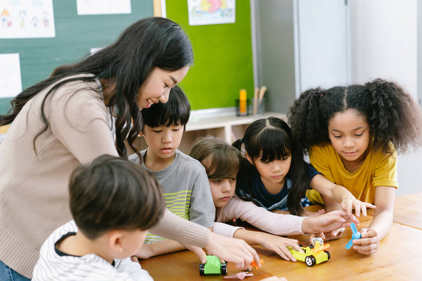 Group of Diverse Elementary School Pupils and Female Asian teacher demonstrating making electric remote control car in science lesson. Education, elementary school, learning, science workshop concept. - Photo, Image