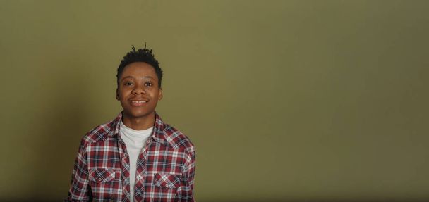 πορτρέτο του νεαρού Αφροαμερικανού με καρό πουκάμισο σε πράσινο φόντο - Φωτογραφία, εικόνα