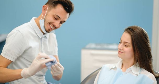 Dentysta pokazuje model szczęki dla młodego pacjenta - Zdjęcie, obraz