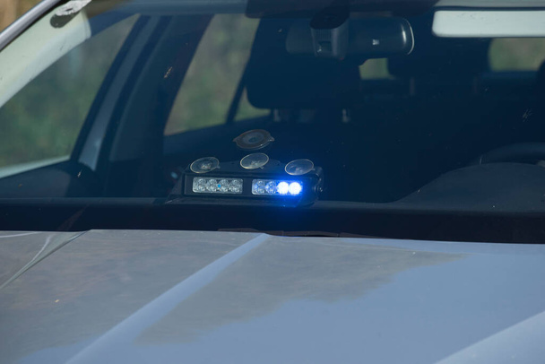 een ongemarkeerde politieauto met een ingeschakeld blauw licht - Foto, afbeelding