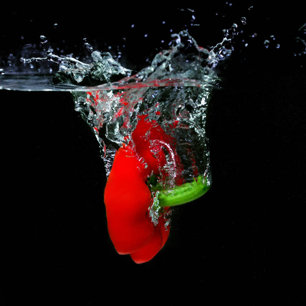 red pepper falling in the boiling water on dark background. Underwater view. Cooking, vegetarian, cooking at home concept - Foto, Imagem