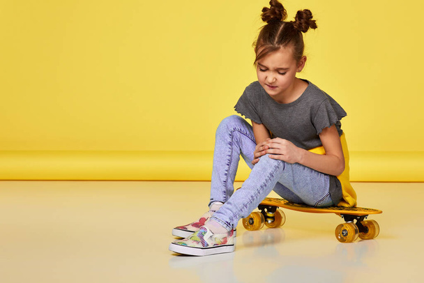 upset little child girl sitting on skateboard - Foto, Imagem