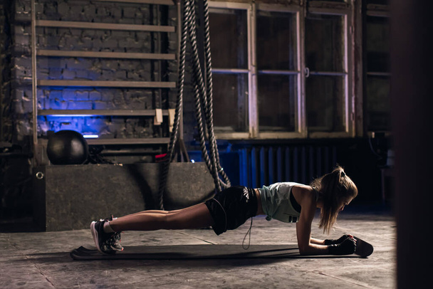 Jeune fille faisant du sport dans la salle de gym. Salle de gym atmosphérique - Photo, image