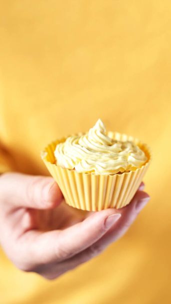 Yellow monochrome bakery. Sustainable cupcake cup. Hold in hand - Φωτογραφία, εικόνα