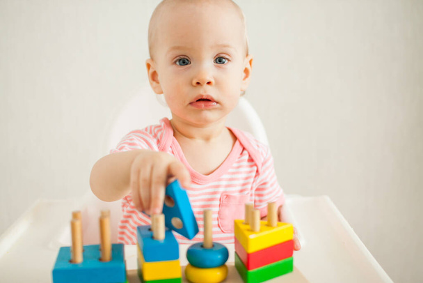 la bambina gioca con un giocattolo educativo - una piramide di legno multicolore. Sviluppo delle capacità motorie e del pensiero logico - Foto, immagini