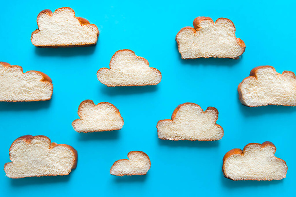 on a blue background, a pattern of cut pieces of a lush cupcake loaf of braided wicker, which are shaped like clouds  - Photo, Image