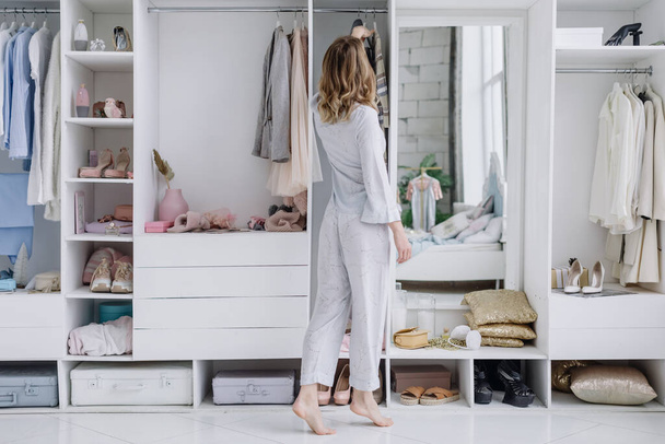 Giovane donna sceglie un abito nel suo camerino moderno - Foto, immagini