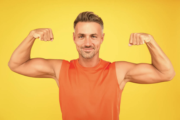 Train hard be strong. Strong man flex arms yellow background. Building strong biceps and triceps. Happy athlete show physical strength. Strong muscle workout. Sport and fitness. Beast mode - Photo, image