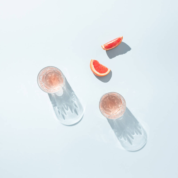 Two glasses of juice with slices of fresh grapefruit on a pastel blue background. Minimal summer aesthetic. Flat lay. - Foto, Bild