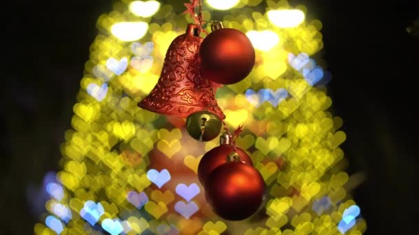 Κόκκινη χριστουγεννιάτικη μπάλα και καμπάνα κυματίζει στην αγάπη φόντο χριστουγεννιάτικο δέντρο. - Πλάνα, βίντεο