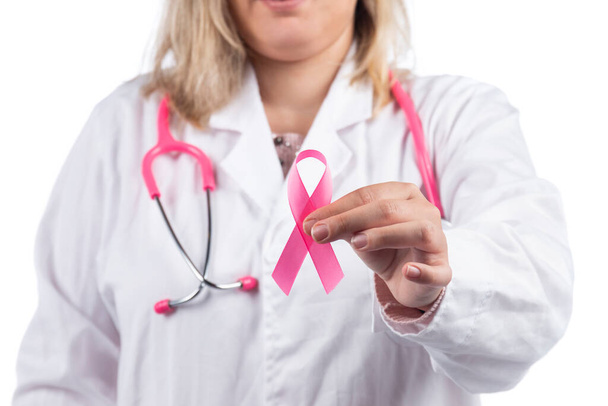 Close up of hands of caucasian doctor woman with pink stethoscope holding breast cancer pink ribbon on a white background. - Fotoğraf, Görsel