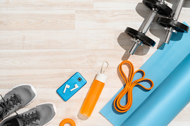 Sports background. Equipment for training and outfit under morning sunlight on wooden floor. Fitness, cross-fit, workout at home. Flat lay, top view, copy space - Photo, Image