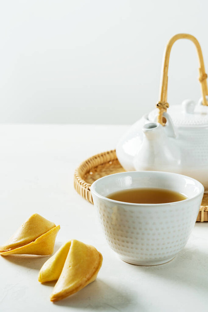 Τσάι σε λευκό ασιατικό κύπελλο με μπισκότα τύχης στο φως φόντο με copyspace. - Φωτογραφία, εικόνα