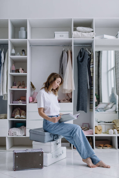 Die junge Frau sitzt in einer modernen Umkleidekabine mit einem Magazin. Mädchen träumt von etwas - Foto, Bild