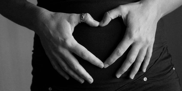 Terhes nő, hogy szív szimbólum a hasán - Fotó, kép