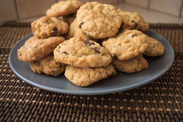 Lekkere chocolade chips koekjes in een grijze plaat op rieten oppervlak. Choco chips cookies.Selectieve focus. - Foto, afbeelding