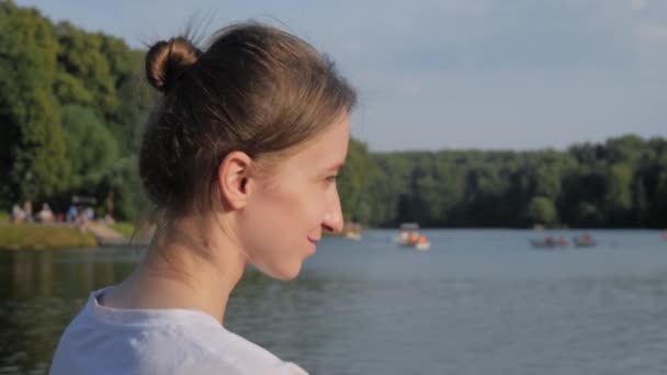 Молода жінка в білій сорочці сидить і дивиться на ставок повільний рух
 - Кадри, відео