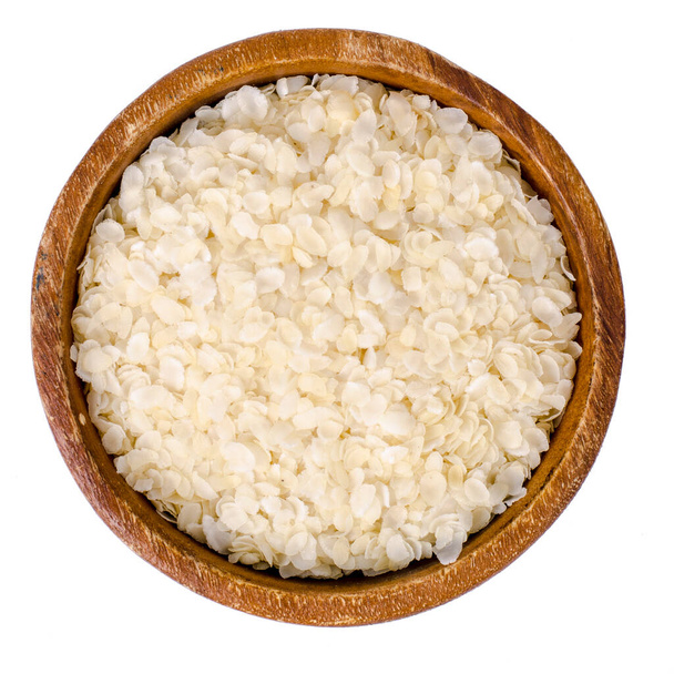 Wooden bowl of flattened rice flakes isolated on white background. Studio Photo - Photo, Image