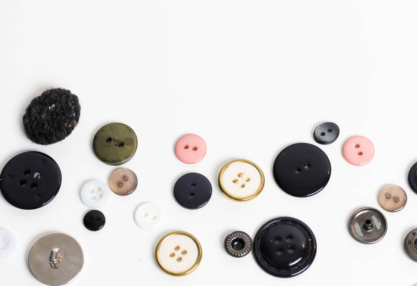 Multicolored plastic buttons for clothes flat lay on a white background. Top view of the table. Accessories for sewing and repairing clothes. High quality photo - Photo, Image