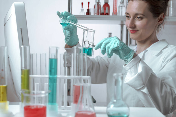 Femme scientifique active versant du liquide dans des béchers dans un laboratoire chimique.. Lifestyle scène extérieure - Photo, image