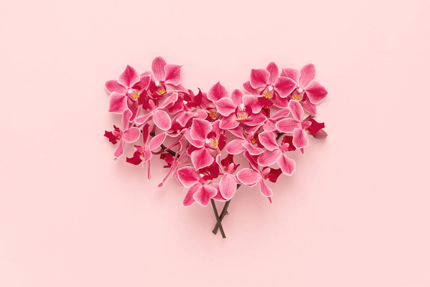 Orchid flowers bouquet in heart shape on pink Valentines day background. - Foto, imagen