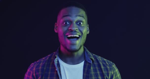 close up retrato de emocional afro-americano cara tocando bochechas em espanto, luzes de néon - Filmagem, Vídeo
