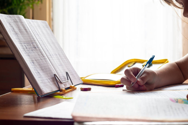 Die Hand des Kindes schreibt während der Hausaufgaben in ein Notizbuch, Nahaufnahme - Foto, Bild