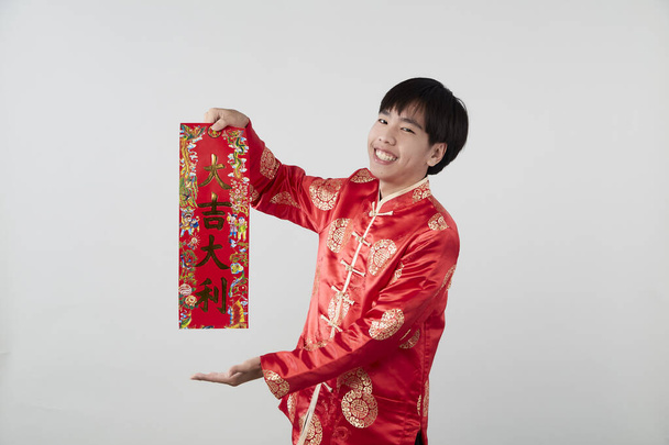 Azjata w tradycyjnym orientalnym stroju gospodarstwa couplet chińskie słowo oznacza gratulacje i najlepsze życzenia dla dobrobytu na jasnoszarym tle dla chińskich koncepcji noworocznych - Zdjęcie, obraz
