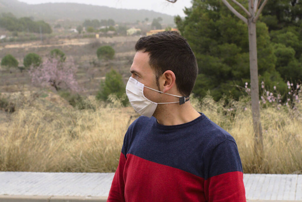 Lonely middle-aged man using reusable face mask outside. Concept: covid19 pandemic and social distancing - Photo, Image