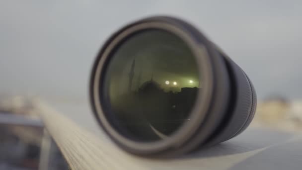 Close-up van fotocamera lens op wazige achtergrond van de stad en de lucht. Actie. Presentatie van nieuwe professionele cameralens. - Video