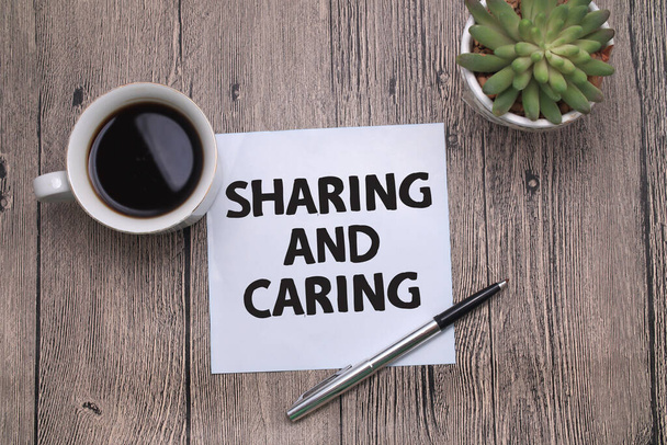 Sharing and caring, text words typography written on paper against wooden background, life and business motivational inspirational concept - Foto, imagen