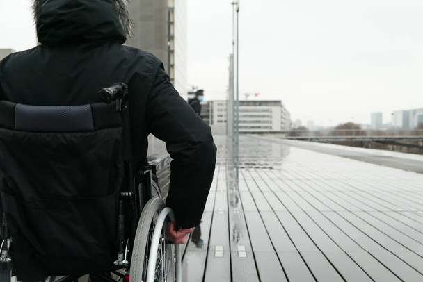 Pojęcie osoby niepełnosprawnej. Mężczyzna na wózku inwalidzkim na ulicy. - Zdjęcie, obraz