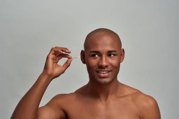 Adult man removing earwax with a cotton bud - Fotoğraf, Görsel