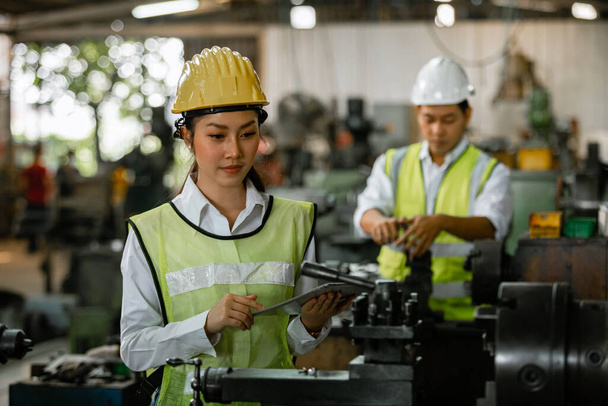 Asiatische Ingenieurin Industrie schwere Arbeiterin trägt Harthut und hält Tablet aussehende Kamera auf Maschinenbereich in Fabrik, Fabrik Industriekonzept. - Foto, Bild