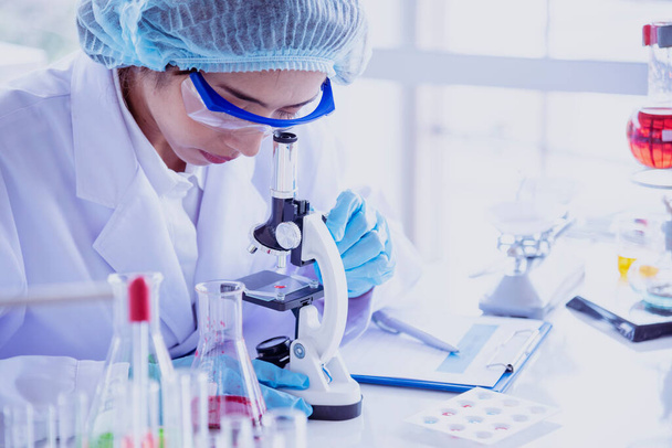 Ženský vědec se podívá na mikroskop, zkumavka s vědeckým testem analyzuje vědecký vzorek v laboratorním výzkumném experimentu, biotechnologie vytvoří kultivovanou vakcínu proti virům. Laboratorní koncept chemie - Fotografie, Obrázek
