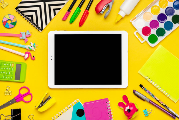 Рюкзак с принадлежностями для школы Ноутбук, ручки, линейка, калькулятор, ножницы, планшет изолирован на желтом фоне - Фото, изображение