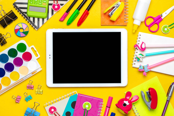 Рюкзак с принадлежностями для школы Ноутбук, ручки, линейка, калькулятор, ножницы, планшет изолирован на желтом фоне - Фото, изображение