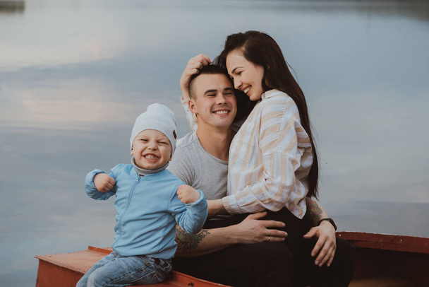 jeune famille blanche heureuse avec leur fils assis dans un bateau - Photo, image