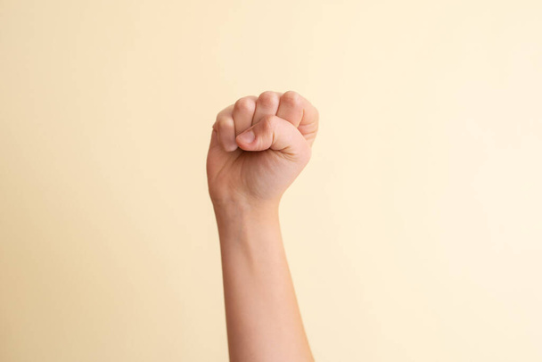 A closeup shot of a fist on the background of a yellow wall - Photo, Image