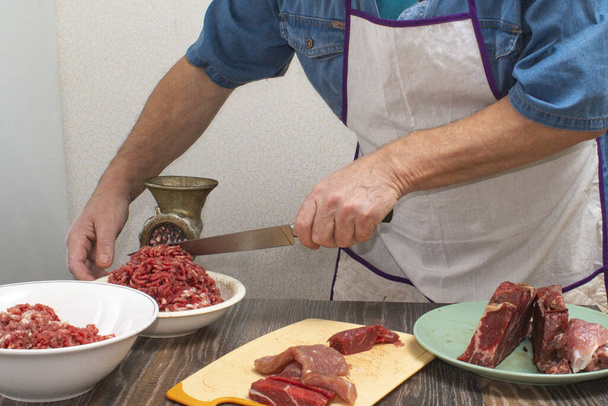 Le chef prépare de la viande hachée dans un hachoir manuel - Photo, image