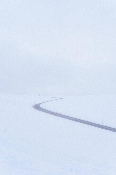 A winding road passing through a snow-covered landscape - Fotoğraf, Görsel