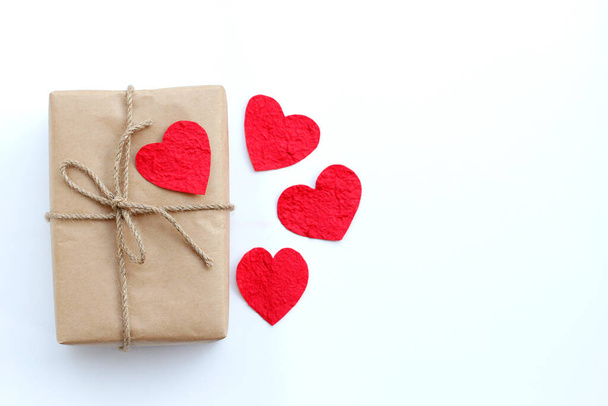 Caja de regalo marrón y corazón de papel rojo en vista superior de fondo blanco con espacio de copia para su diseño. Día de San Valentín y concepto de amor. - Foto, Imagen