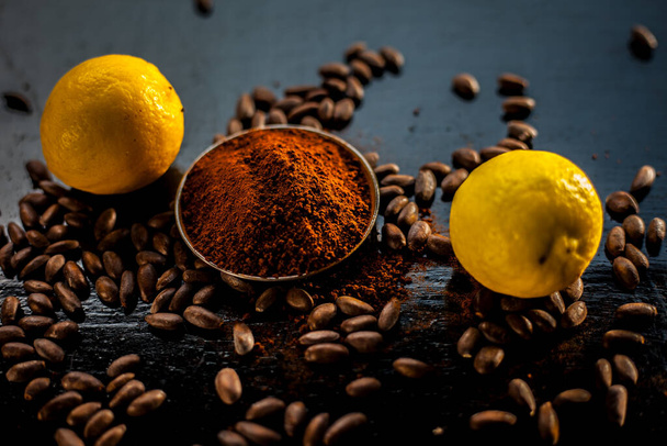 Best home remedy or face mask to remove tan at home consisting of some coffee beans powder and lemon juice on a black colored wooden surface. - Фото, зображення