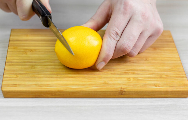 Snijd de citroen. Mannen handen snijden een citroen.. - Foto, afbeelding