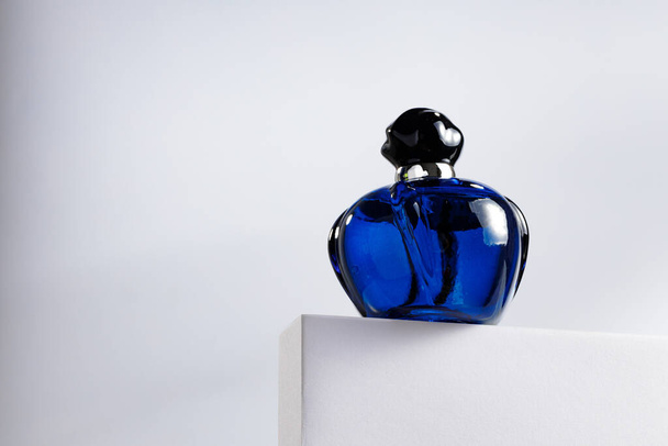Fragrance bottle on gray block against gray background - Φωτογραφία, εικόνα