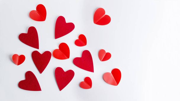 Red hearts of different shapes and sizes lie on a white background. The concept of a festive background with a flat layout, copying of space - Fotografie, Obrázek