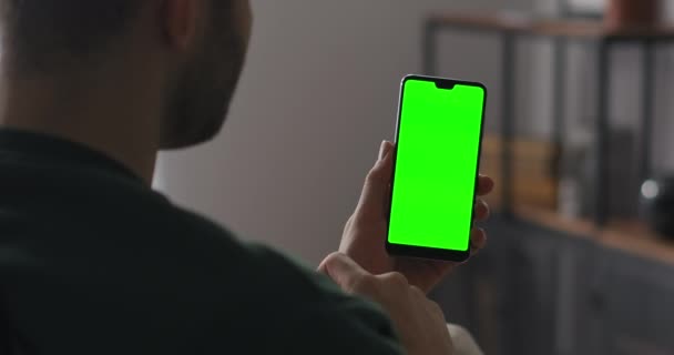 Мужчина использует современное приложение, поворачивается и постукивает по экрану смартфона, технологию зеленого экрана на гаджете - Кадры, видео