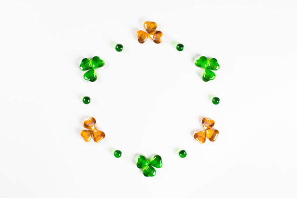 Circle frame of green and orange glass hearts shamrocks on white background  - 写真・画像